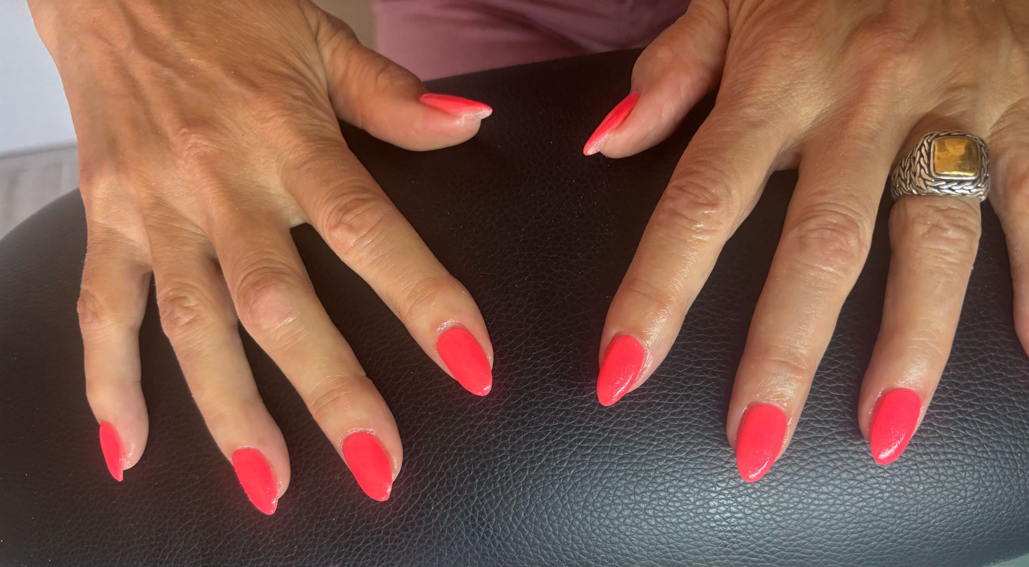 Koraalkleurige nagels op het zwarte kussen